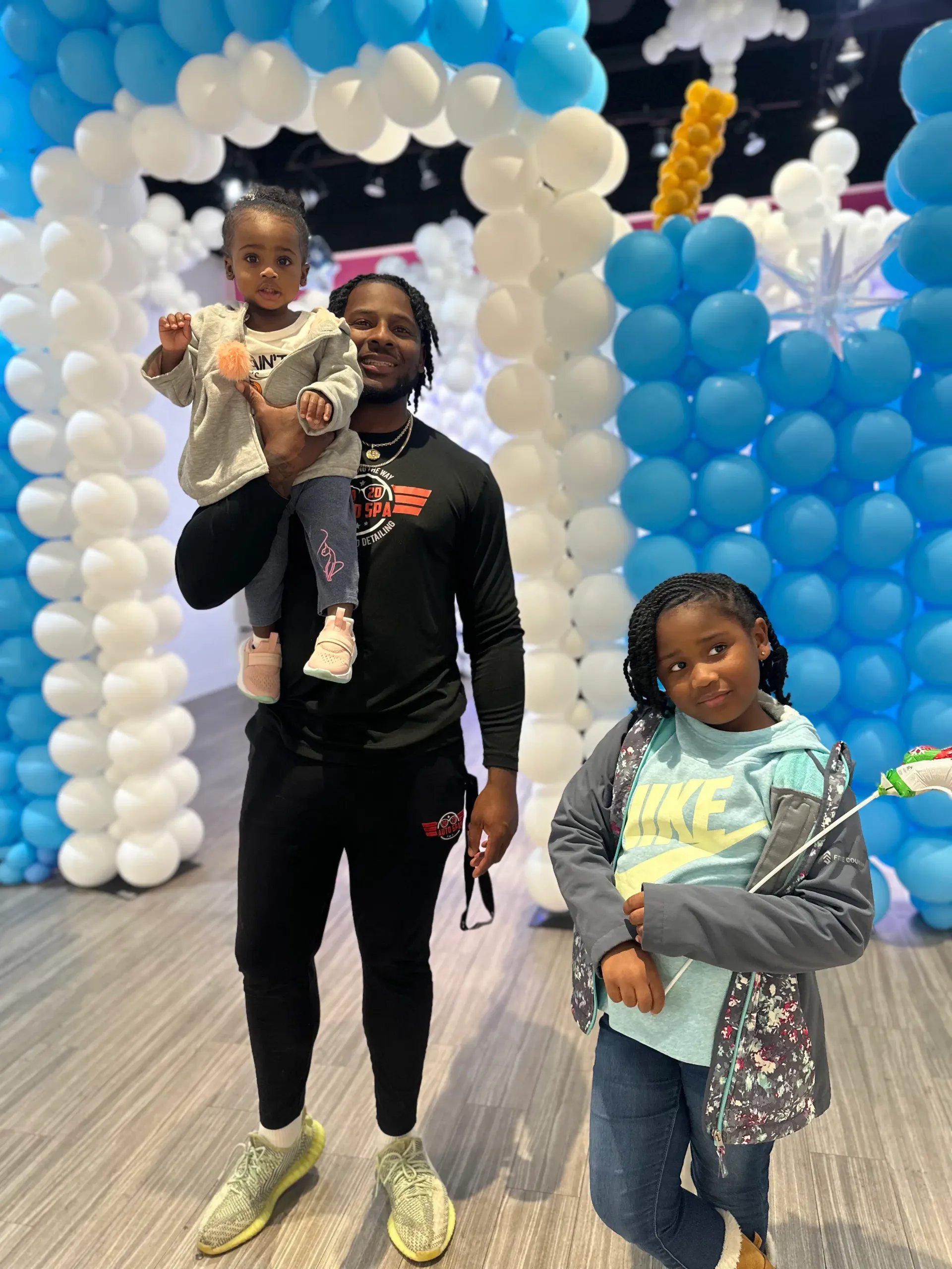 Coach Darnell Newman with two of his children surrounded by blue and white balloons